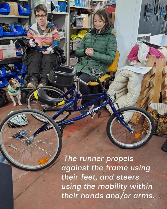 A photo of a blue child frame runner in a workshop with the text stating 'The runner propels against the frame using their feet, and steers using the mobility within their hands and/or arms.'
