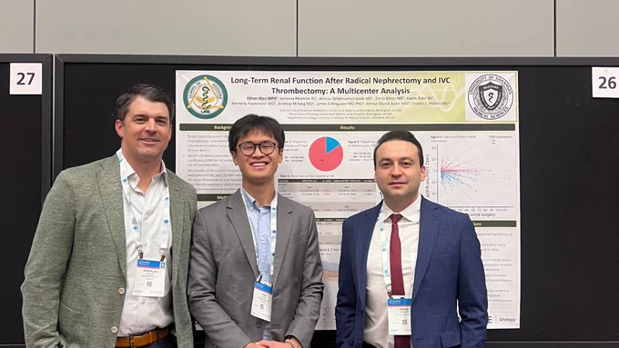 Group photo of three conference attendees standing in front of a research poster titled “Long‑term Renal Function After Radical Nephrectomy and IVC Thrombectomy: A Multicenter Analysis.” The poster displays study background, methods, results, and data visualizations, with UAB Medicine branding visible.
