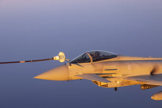 An RAF Typhoon in flight, undergoing air-to-air refuelling with blue skies in the background.