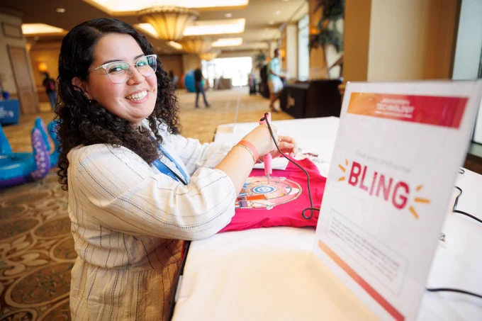 Photo of a person smiling at the camera while participating in arts and crafts. 