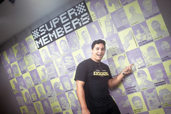 @solgab hyped up pointing at a massive wall covered in Solana ecosystem memes, CT legends and Brazilian crypto figures, all displayed in a purple and yellow grid style.