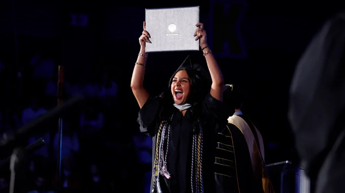 A student celebrates with their diploma.