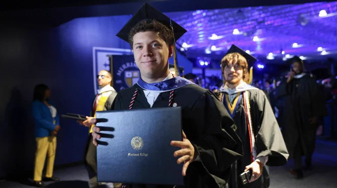 A student holds their diploma as they leave Commencement. 