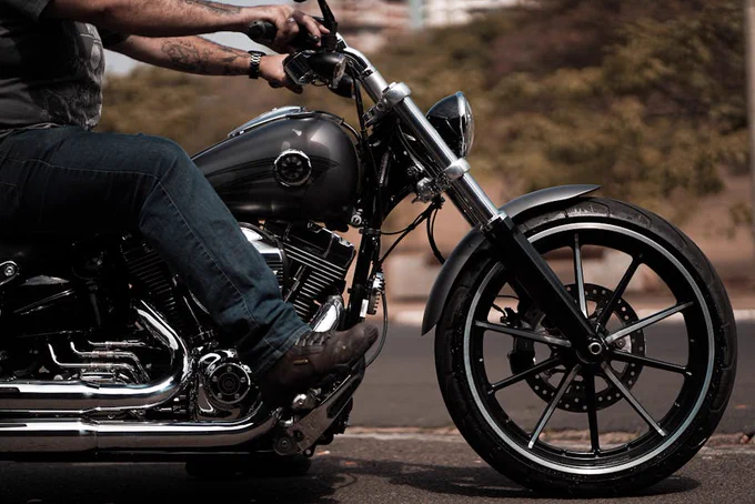 A close-up image of a biker in leather riding a motorcycle on an open road.