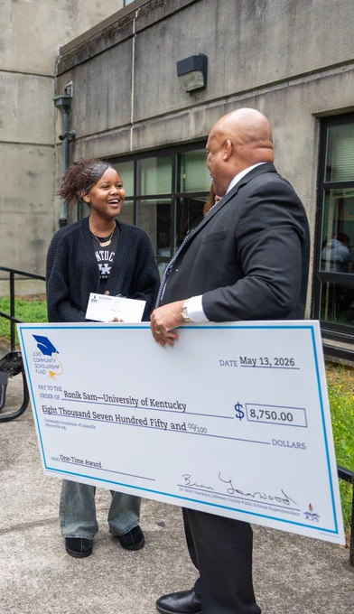 Superintendent Dr. Brian Yearwood presents Fern Creek High School student Ronik with a check for $8,750.
