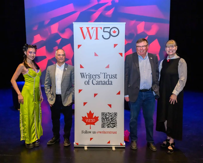 Jenny Heijun Wills, Marcello Di Cintio, Guy Vanderhaeghe, and Shelley Youngblut pose on stage next to a Writers' Trust of Canada.   