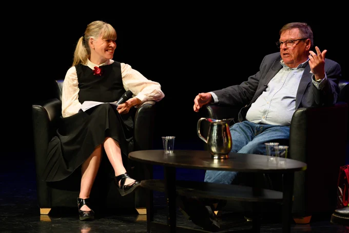 Guy Vanderhaeghe speaking, with Shelley Youngblut seated next to him on stage. 