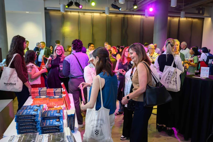 Event attendees mingle next to a table with event authors books. 