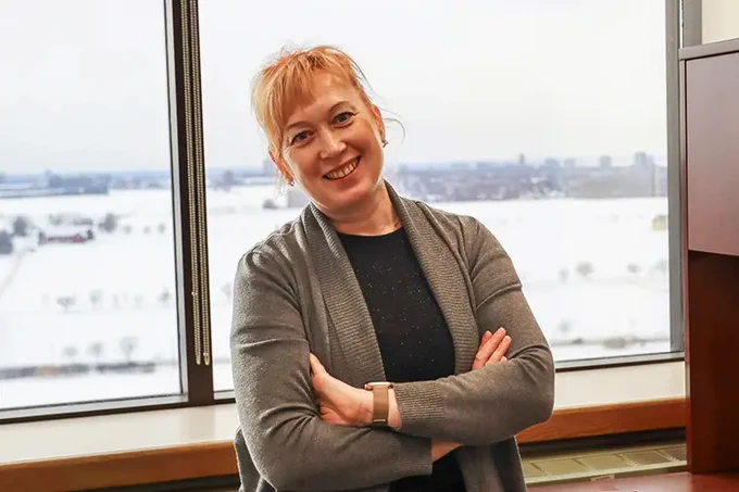 IMAGE: Portrait of Olessia Jouravlev standing in an office, smiling for the camera. (Photo Credit: Brenna Mackay)