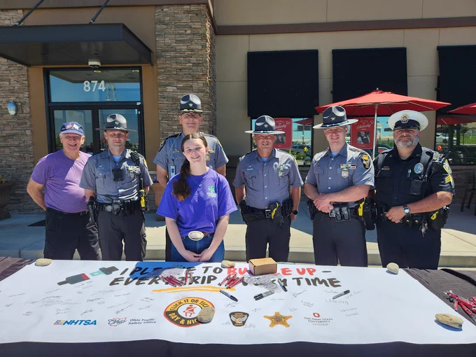 Four troopers and three of our safety partners stand at a table promoting Click-it or Ticket. 