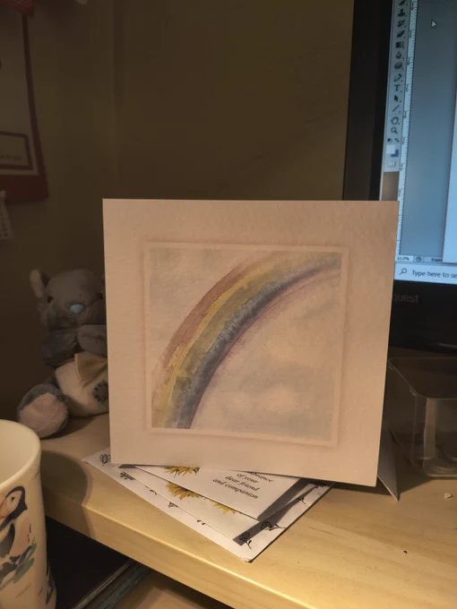 A white greetings card with a rainbow on the front 