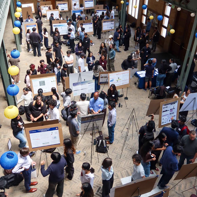 Overhead view of the Data Discovery symposium featuring attendees and research posters.