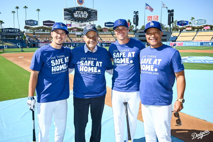 A photo of Tommy Edman, Joe Torre, Alex Call and Dave Roberts on the field wearing the Joe Torre “Safe At Home” t-shirts during batting practice.