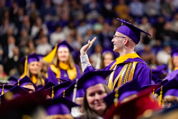A graduate waves to someone during a commencement ceremony.