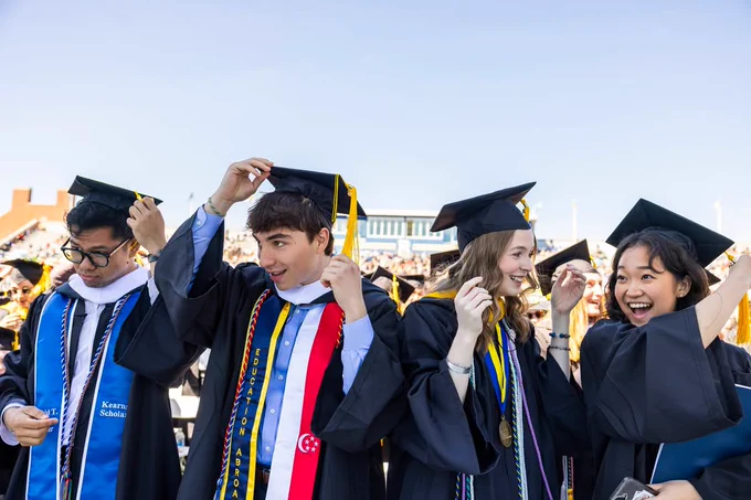 A row or graduates move their tassels from one side to another. 