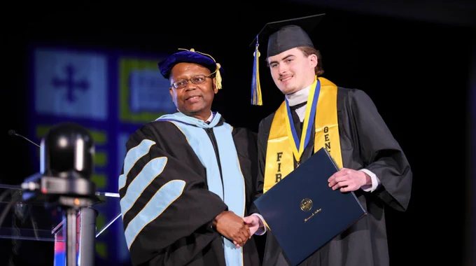 A graduate accepts their diploma at Commencement. 