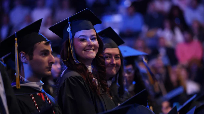 Graduates smile at Commencement. 
