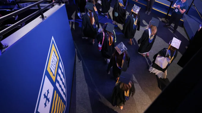 Graduates walk into Lawler Arena for Commencement. 