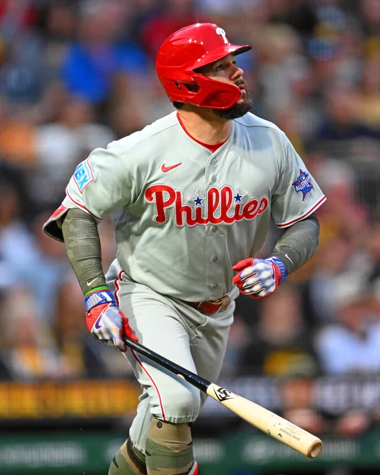 Kyle Schwarber watches a home run sail out of the park Friday night. He wears a gray Phillies uniform with red lettering and white trim.