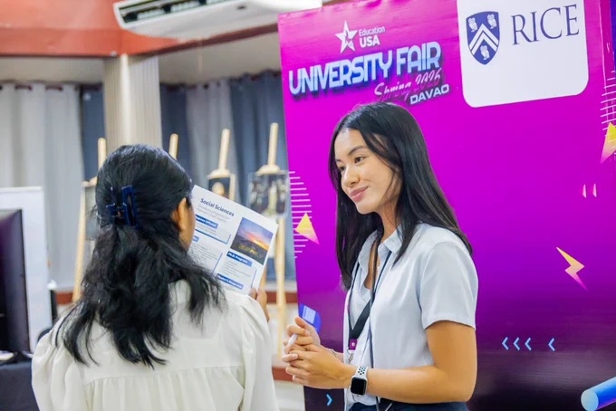 A U.S. university representative speaking with a fair participant.