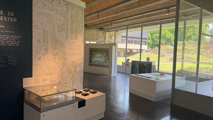 Interactive museum displays with a glass wall looking out onto a Roman bath house.