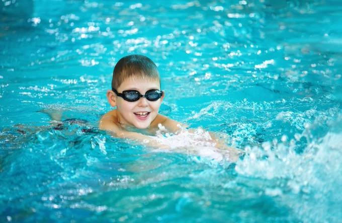A picture of a boy swimming at a local public swimming pool.