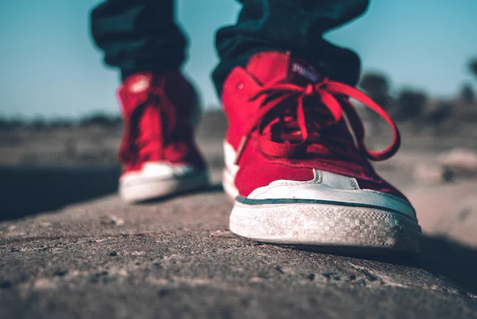 Stylish red sneakers on a rugged outdoor path, highlighting fashion and adventure.