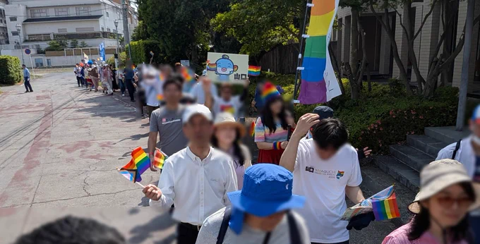 パレードの写真。多くの人たちが列になり歩いている写真。