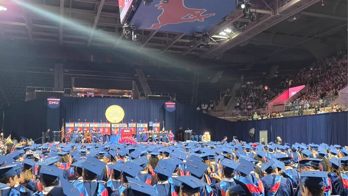 A sea of graduating students from SMU Cox School of Business sit facing the stage in in their caps and gowns waiting for the 2026 Commencement Ceremony to begin.