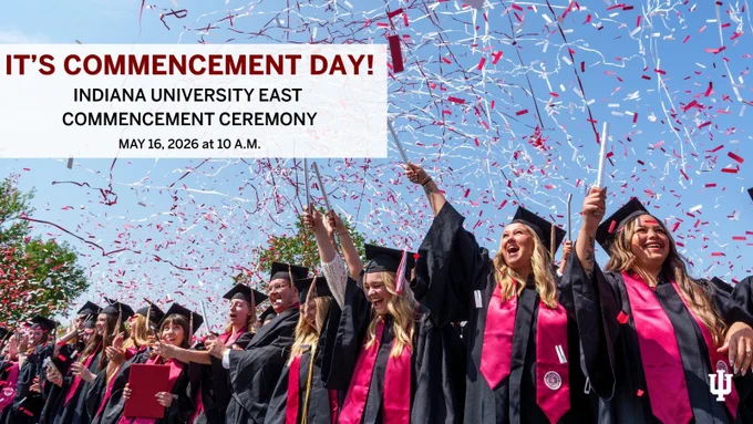 A group of graduates in academic gowns and caps celebrate with raised hands as red and white confetti falls around them. A large sign reads, "It's Commencement Day! Indiana University East Commencement Ceremony, May 16, 2026, at 10 A.M." The Indiana University East logo is visible.