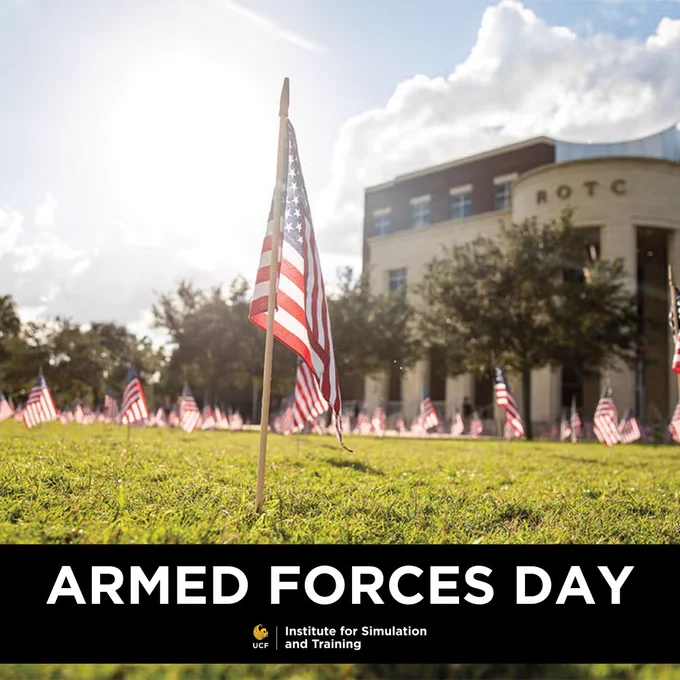 American flags planted on a lawn in front of an ROTC building, with a banner announcing Armed Forces Day