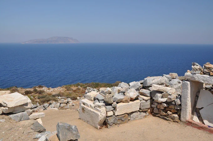 Ancient Greek grave on the island of Ios, photographed in 2013. Grave made of white stone, traditionally believed to be that of Homer, a blind, illiterate poet who wrote the Iliad and the Odyssey. In the background, the Aegean Sea and another Cycladic Island.