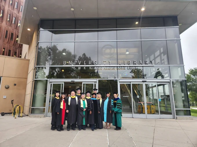 Three photos show a group of graduates and faculty in academic caps and gowns posing outside the glass-front entrance of the University Library & W.K. Kellogg Arabian Horse Library, with reflections in the windows and parts of the campus building visible in wider shots.