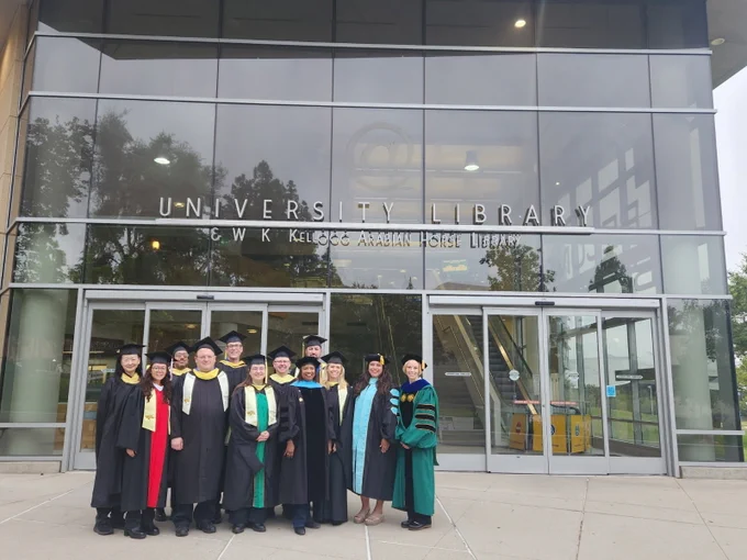 Three photos show a group of graduates and faculty in academic caps and gowns posing outside the glass-front entrance of the University Library & W.K. Kellogg Arabian Horse Library, with reflections in the windows and parts of the campus building visible in wider shots.