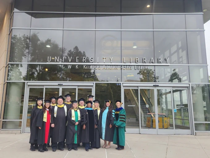 Three photos show a group of graduates and faculty in academic caps and gowns posing outside the glass-front entrance of the University Library & W.K. Kellogg Arabian Horse Library, with reflections in the windows and parts of the campus building visible in wider shots.