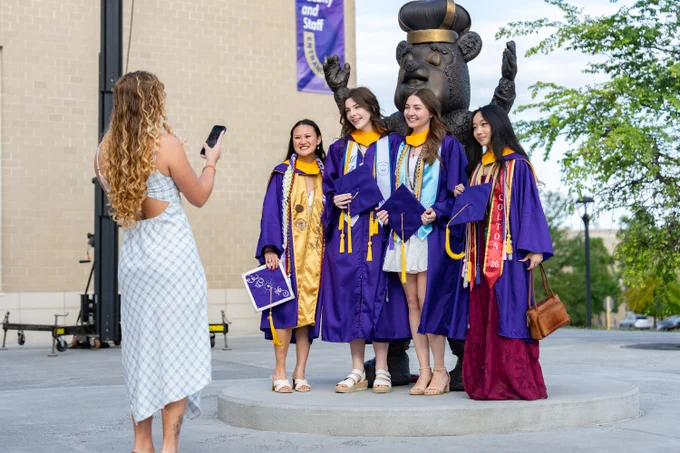 A group of graduates poses for a photo in front of the bronze Duke Dog statue.