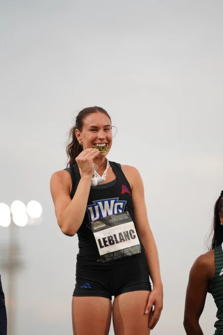 chloe leblanc biting a gold medal at the asun championship