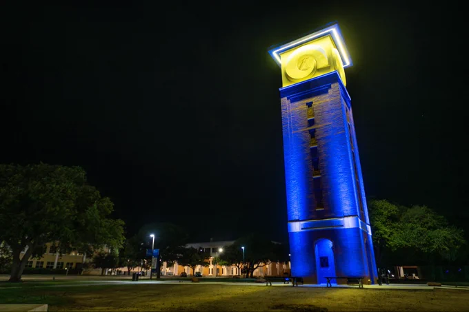 A tower lit up blue and yellow against a dark sky.