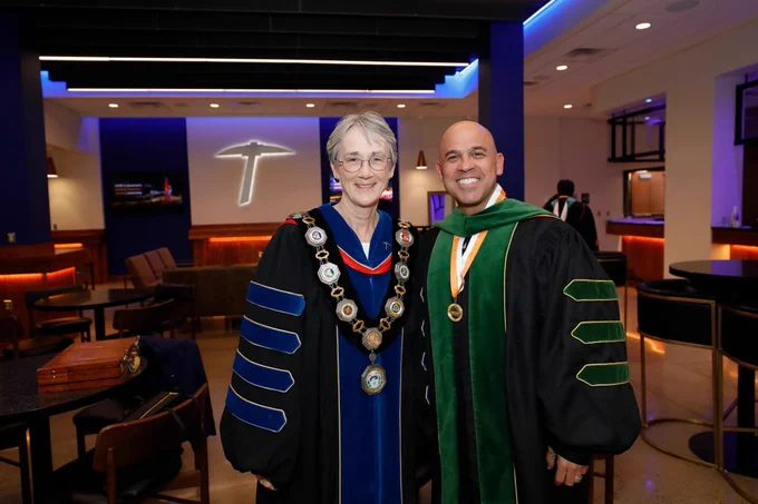 UTEP President Heather Wilson Regent Nolan Perez from the University of Texas System Board of Regents in a room with the UTEP logo in the background.