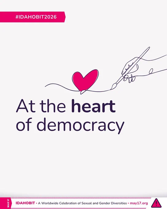 Line art of a hand holding a brush and drawing a heart. At the centre, the text reads “At the heart of democracy.” A pink banner underneath includes “IDAHOBIT – A Worldwide Celebration of Sexual and Gender Diversities – may17.org” and a pink triangle with an exclamation mark, which is the logomark of IDAHOBIT.