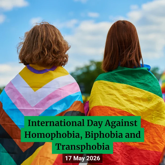 Two people from behind wearing pride flags around their shoulders.