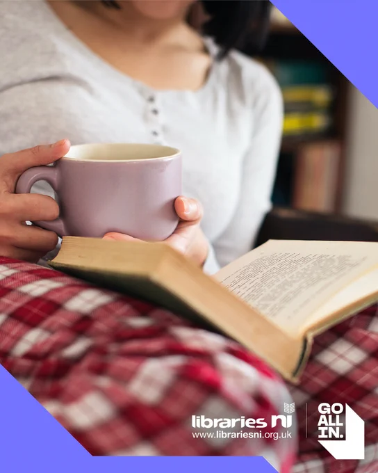 A person holding a mug and reading a book, with the Libraries NI logo visible.