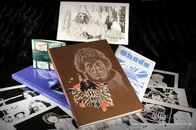 "DNA of Doctor Who - The Graham Williams Years" book, shown with the earlier Philip Hinchcliffe edition, a selection of John Ridgway art prints, the new edition of "Shada" fanzine - plus the original sketch for John Ridgway's "Stones of Blood" art.