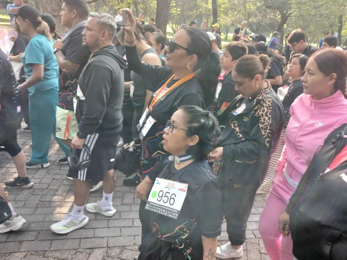 Fotografía a color al interior del Bosque de Chapultepec, en la que aparecen de perfil Ruth Francisca López Gutiérrez, Directora General del Instituto de las Personas con Discapacidad de la Ciudad de México y personas que participaron en la Carrera Corre por Ti, Camina Conmigo 2025.