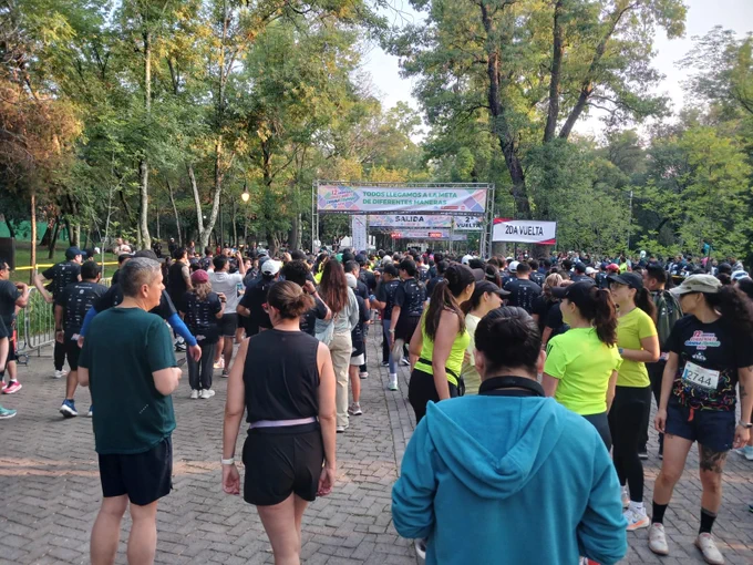Fotografía a color al interior del Bosque de Chapultepec, en la que aparecen personas asistentes a la Carrera Corre por Ti, Camina Conmigo 2025 preparándose para la salida.