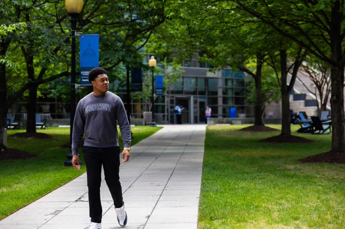 A man in Georgetown shirt walks on Law Center's patio