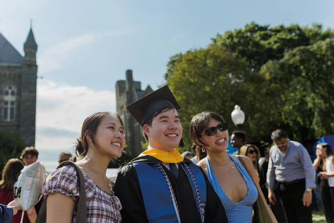 A man in grad regalia poses with two women