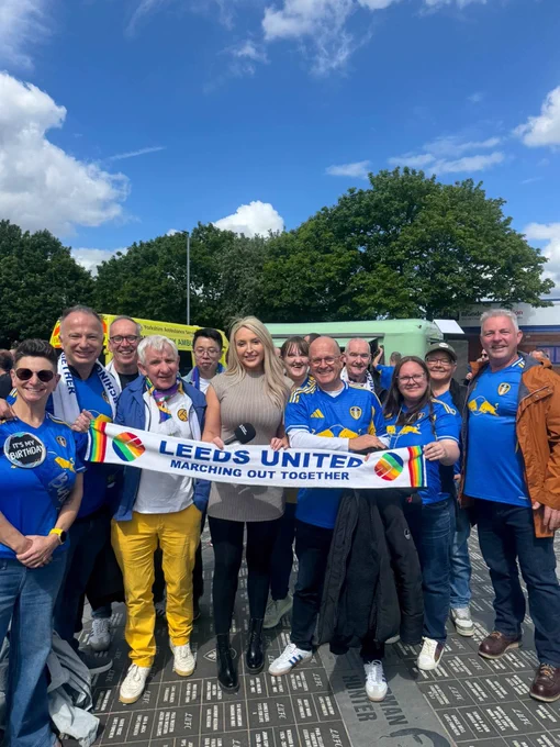Members of Marching Out Together & Emma Jones out front of the east stand holding up a Marching out together scarf