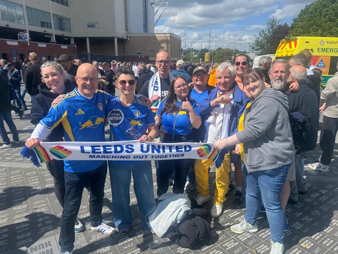 Members of Marching Out Together out front of the east stand holding up a Marching out together scarf