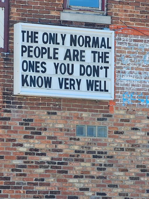 Sign on a brick building that says "the only normal people are the ones you don't know very well"